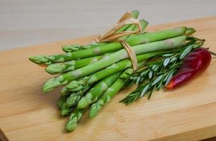 Raw asparagus on wooden board and wooden background photo