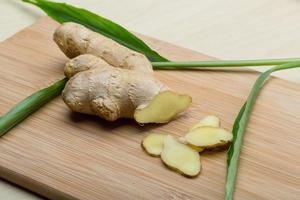 Ginger root on wooden board and wooden background photo