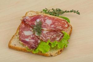 Salami sandwich on wooden background photo