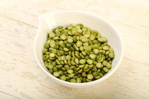 Green peas in a bowl on wooden background photo