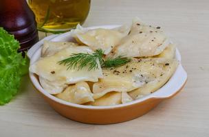 Vareniki in a bowl on wooden background photo