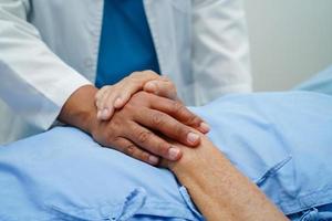 médico tomados de la mano paciente anciana asiática, ayuda y atención en el hospital. foto