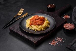Pasta with beef meatballs in tomato sauce with spices and herbs on a dark background photo