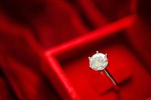 anillo de diamantes en caja de regalo de joyería sobre fondo de tela roja foto