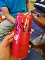 Jakarta, Indonesia in July 2022. A hand is holding a can of fizzy drink, coca - cola zero sugar. photo