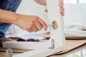 Man assembling white chair furniture at home photo