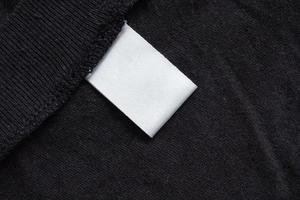 Blank white laundry care clothing label on black fabric texture photo