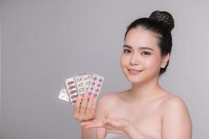 Beautiful woman sitting with pills in hands on white background isolated photo