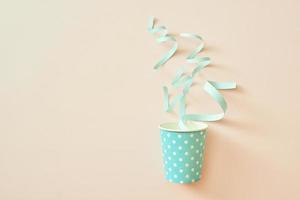 Celebration concept. Paper cup with confetti on a beige background. photo