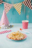 Birthday party items with popcorn on table photo