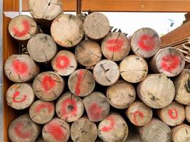 Old round teak logs are stacked together to build a house, The wooden poles from the transportation in Thailand are colored red on the wood to make them stand out in sight. photo
