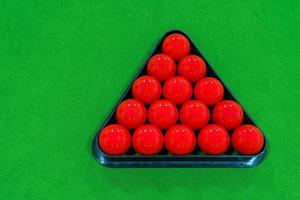 Top view 15 red snooker balls in a black frame on a green velvet snooker table. photo