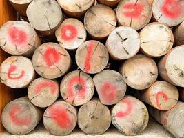 Old round teak logs are stacked together to build a house, The wooden poles from the transportation in Thailand are colored red on the wood to make them stand out in sight. photo