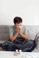 Man feeling cold, lying in the sofa and blowing his nose photo