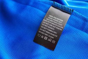 Black laundry care washing instructions clothes label on blue jersey polyester sport shirt photo