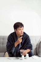 Handsome young man with pill and glass of water at home photo