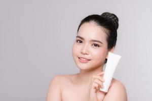 Beautiful asian Woman Face Portrait holding and presenting cream tube product photo