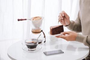 A young man is sitting in coffee shop drinking coffee and eating cake. With copy space photo