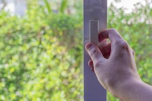 Hand hold mosquito net wire screen handle on house window photo