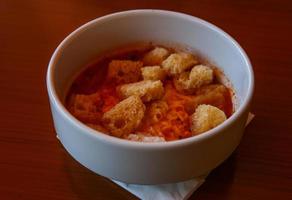 sopa de tomate en un bol sobre fondo de madera foto