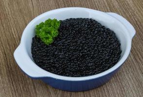 Black caviar in a bowl on wooden background photo