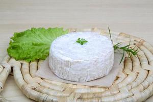 queso brie sobre tablero de madera y fondo de madera foto