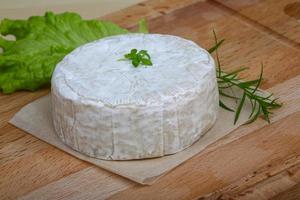 queso camembert sobre tabla de madera y fondo de madera foto