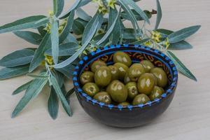 aceitunas verdes en un recipiente sobre fondo de madera foto