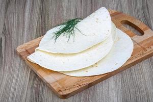 tortillas en tablero de madera y fondo de madera foto