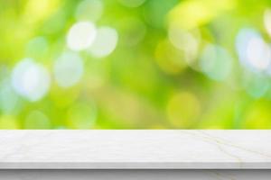 Marble table top with blur green leaf bokeh nature background photo