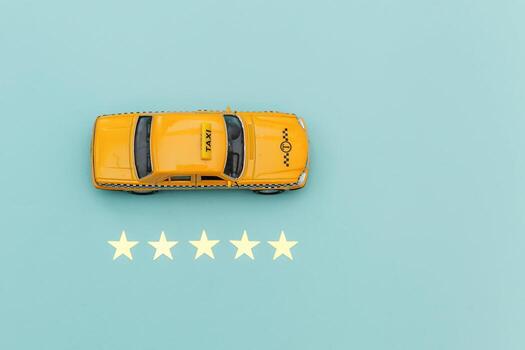 Yellow toy car Taxi Cab and 5 stars rating isolated on blue background. Smartphone application of taxi service for online searching calling and booking cab concept. Taxi symbol. Copy space. photo