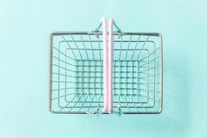 Small empty supermarket grocery shopping basket toy isolated on blue pastel colorful trendy background. Copy space. Sale buy mall market shop online shopping consumer concept. photo