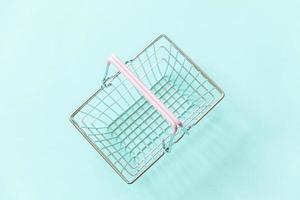 Small empty supermarket grocery shopping basket toy isolated on blue pastel colorful trendy background. Copy space. Sale buy mall market shop online shopping consumer concept. photo