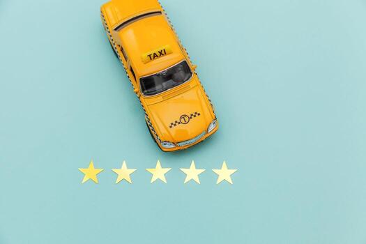 Yellow toy car Taxi Cab and 5 stars rating isolated on blue background. Smartphone application of taxi service for online searching calling and booking cab concept. Taxi symbol. Copy space. photo