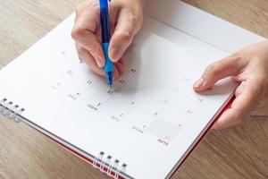 Woman hand with pen writing on calendar date business planning appointment meeting concept photo