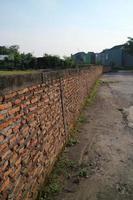 una pared larga con ladrillos rojos al borde de un campo de arroz foto