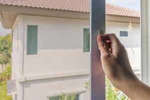 Hand hold mosquito net wire screen handle on house window photo