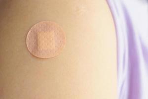 Close up circle brown adhesive bandage on patient arm after medicine injection or vaccination photo