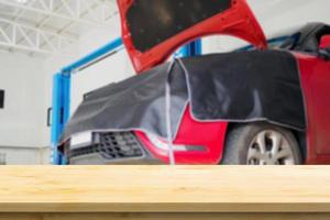 Empty wood table top with car service centre auto repair workshop blurred background photo