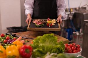 female Chef holding beef steak plate photo