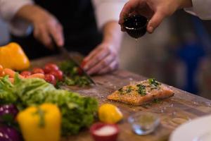 Chef hands preparing marinated Salmon fish photo