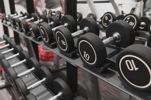 Closeup of kilogram dumbbells placed on a dumbbell rack at the gym. Weight training equipment. photo