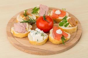 Assorted tapas on wooden board and wooden background photo