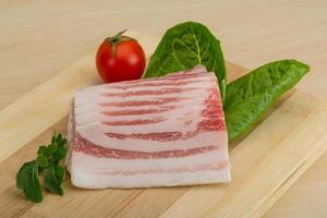 Bacon on wooden board and wooden background photo
