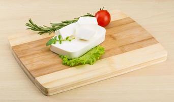 Feta cheese on wooden board and wooden background photo