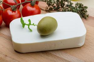 Feta cheese on wooden board and wooden background photo