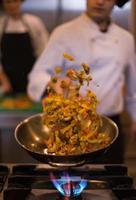 chef volteando verduras en wok foto