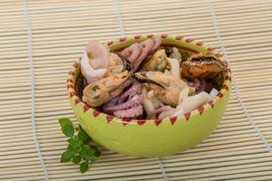 Seafood cocktail in a bowl on wooden background photo