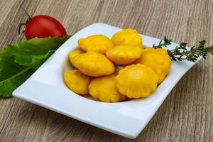 Pickled patissons in a bowl on wooden background photo