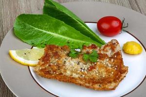 Pork schnitzel on the plate and wooden background photo